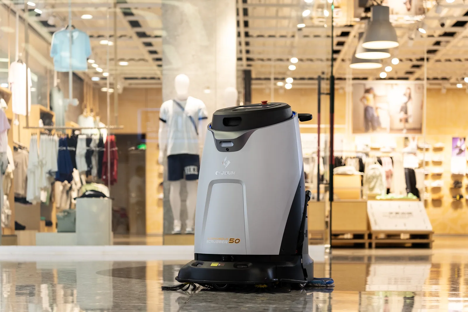 Gausium Scrubber 50 lavando corredor de shopping em frente a vitrine